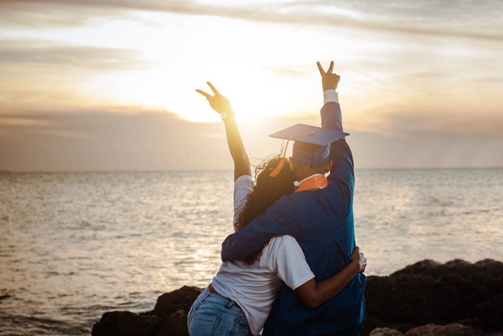 Graduate and mother standing on a beach acing the sunset